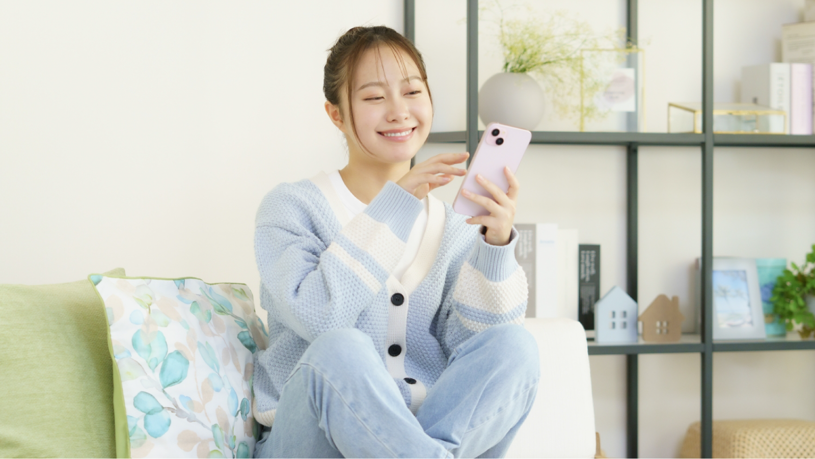 部屋でスマホを見ている笑顔の若い女性